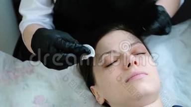 美容师用棉垫<strong>摩擦</strong>病人`眼睑。 肉毒杆菌和睫毛层压。 美容治疗。